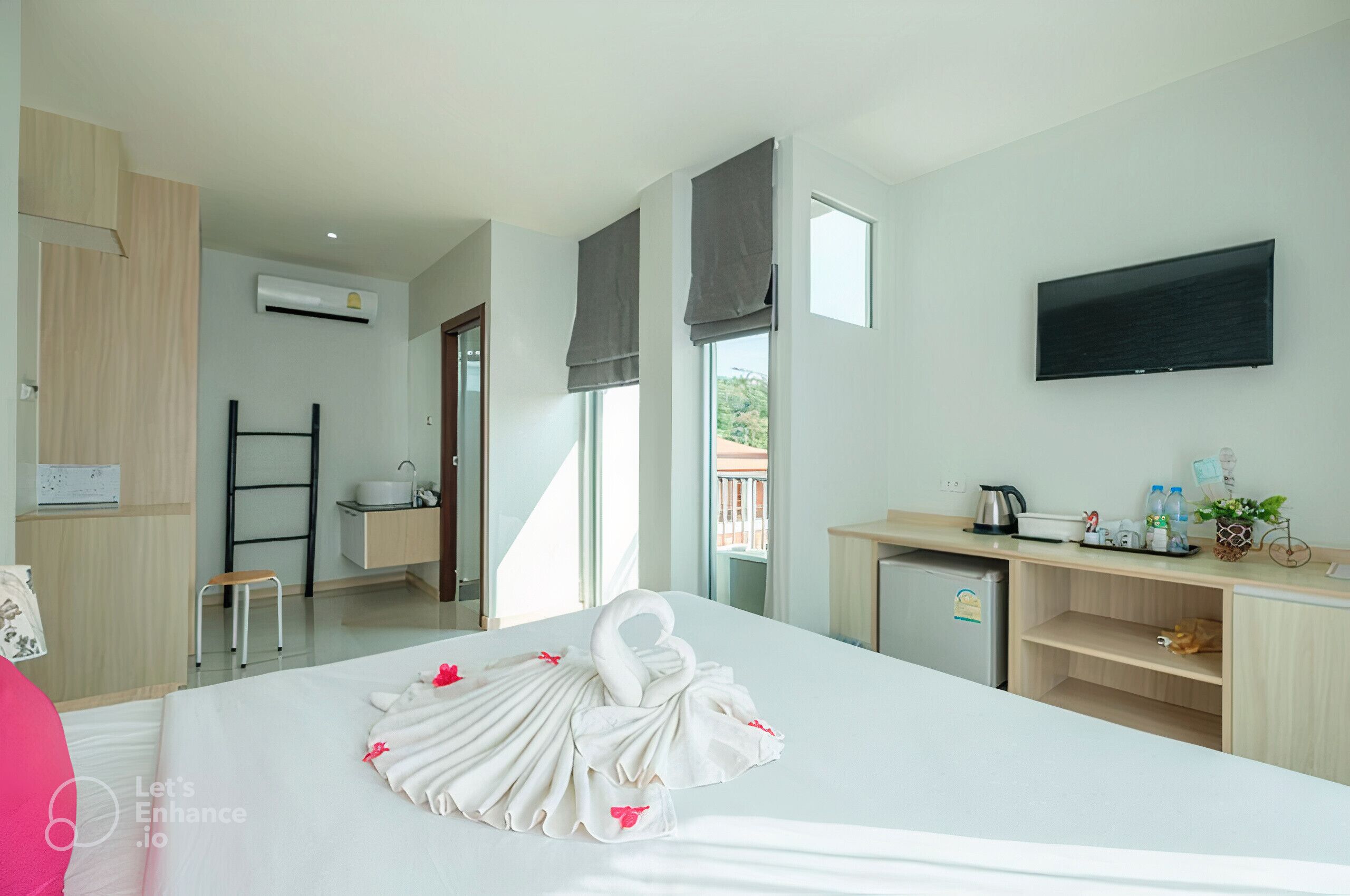 Habitación de hotel con cama, escritorio, televisión y vista al balcón.