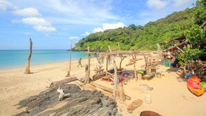 Une plage avec des structures en bois et un kayak aux couleurs vives.