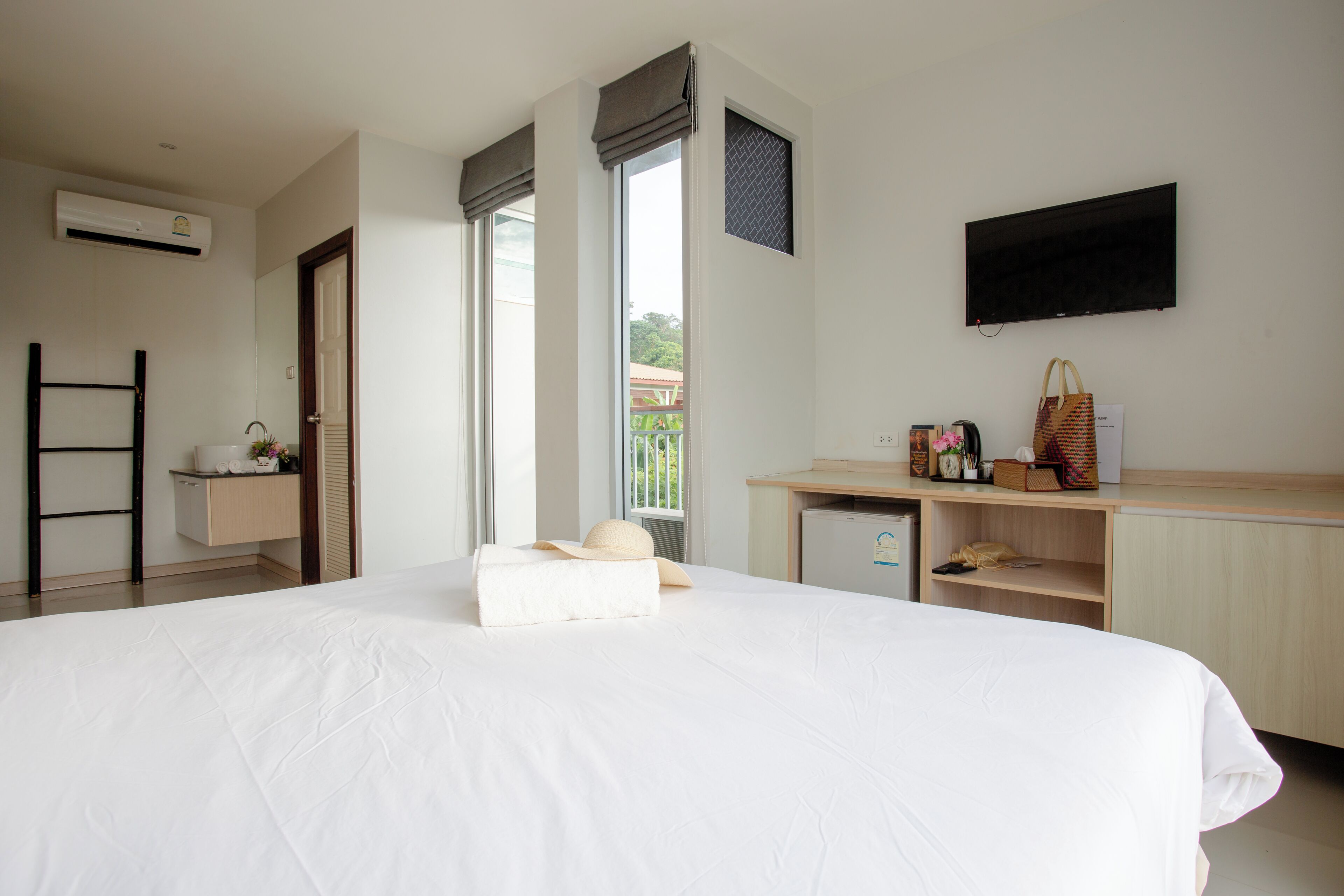 Habitación de hotel con una cama grande, un escritorio con computadora, televisión y ventana con vistas.