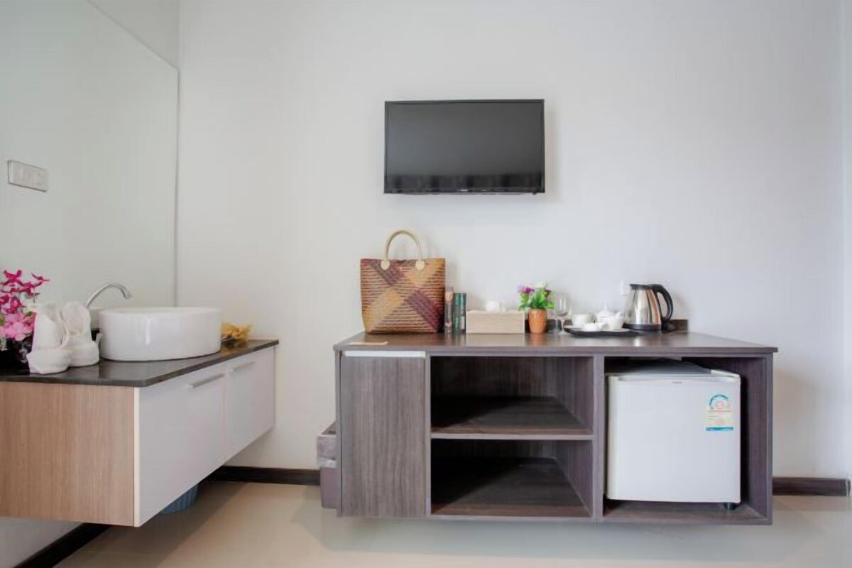 Ein modernes Badezimmer mit Waschbecken, Spiegel und einem flachbildfernseher an der Wand.