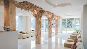 Un espace d’accueil moderne, doté d’un comptoir de réception en bois, d’un coin salon et de grandes fenêtres offrant une vue sur l’extérieur.