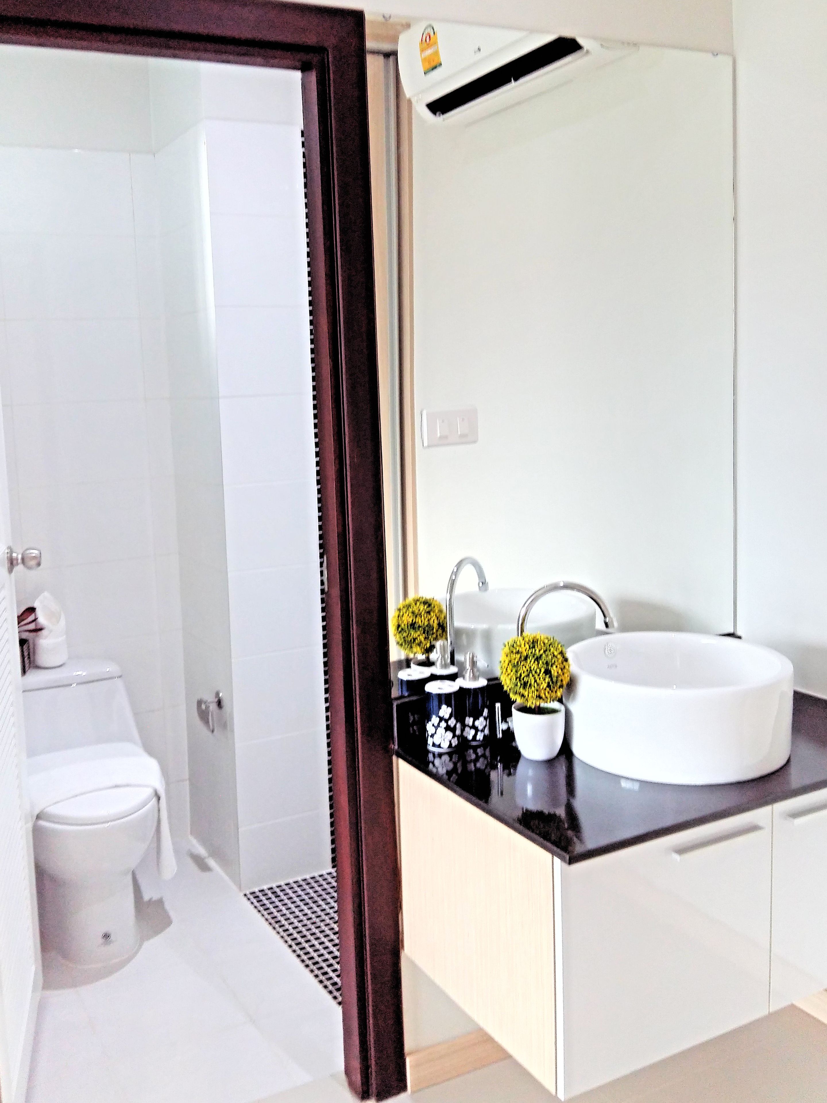 A modern bathroom with a white sink, black countertop, and a large mirror.