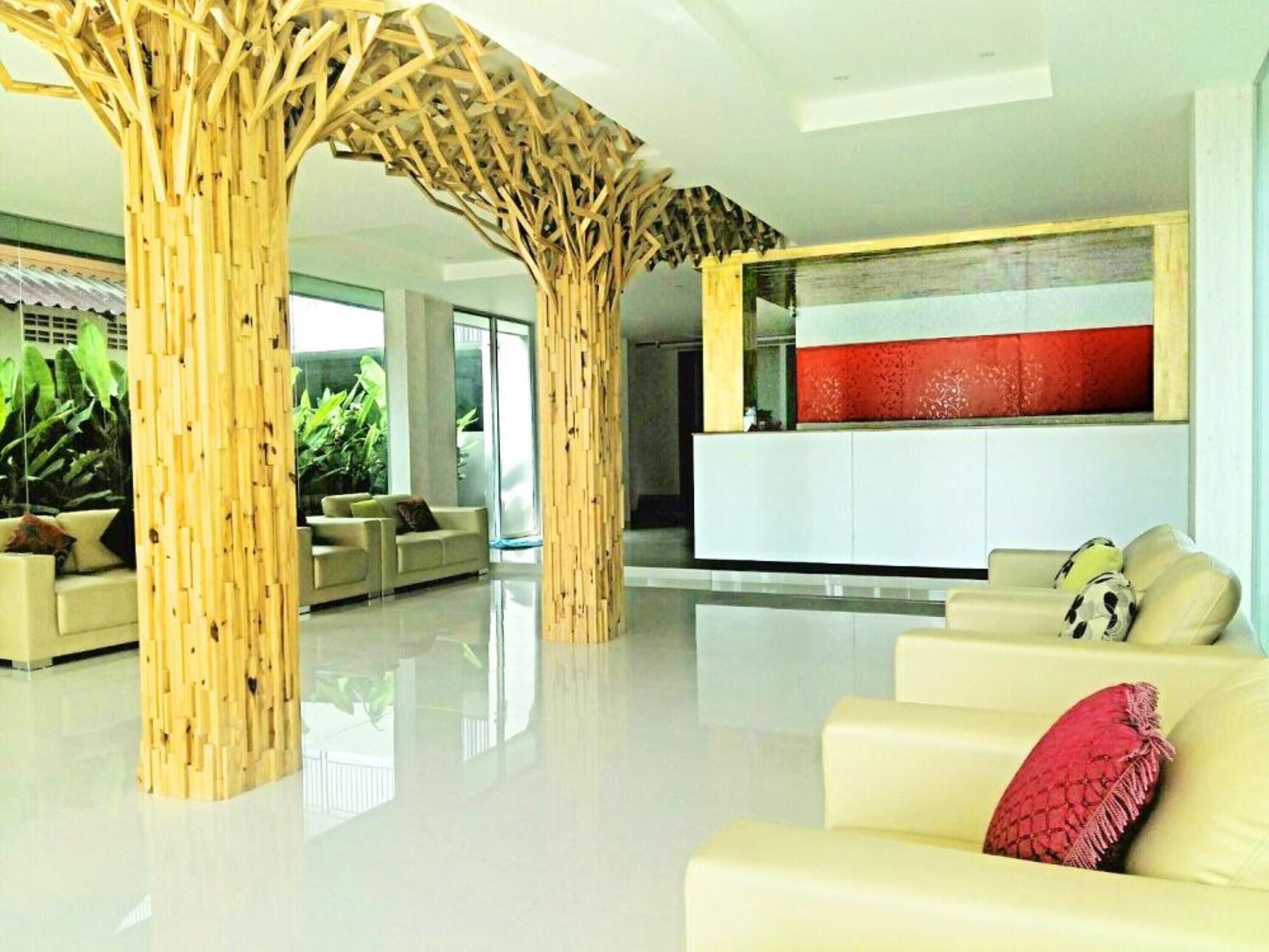 Um hall moderno com uma mesa de recepção, um sofá branco com uma almofada vermelha e uma estrutura decorativa de madeira.