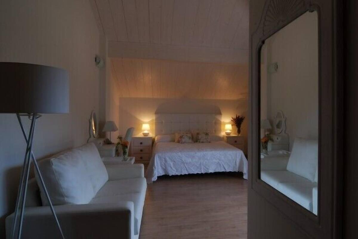 A bedroom with a bed, bedside tables, a floor lamp, and a large mirror.