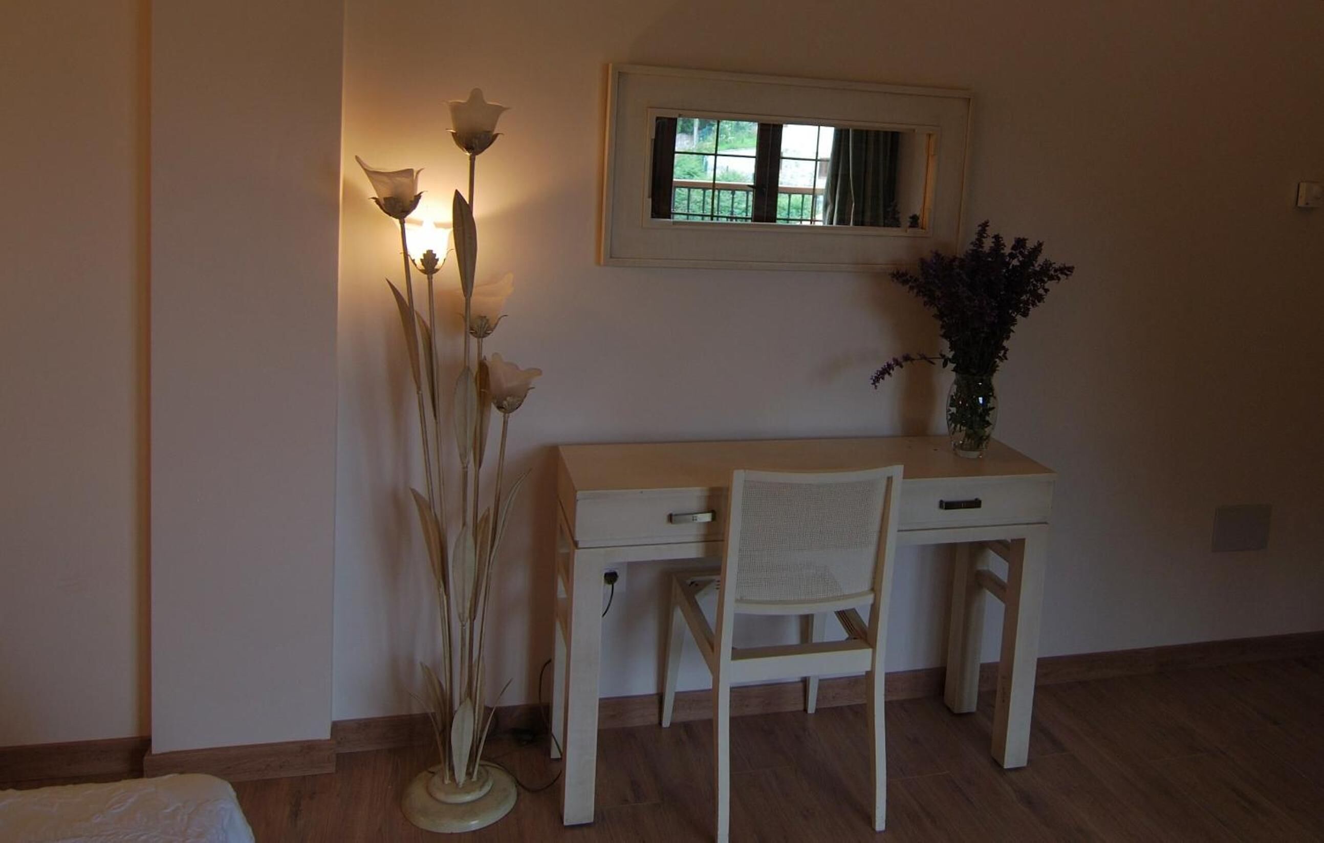 Ein Zimmer mit Schreibtisch, Stuhl und einer Blumenvase.