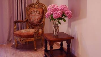 Una habitación con una silla de madera y una mesa pequeña con un jarrón de flores rosas.
