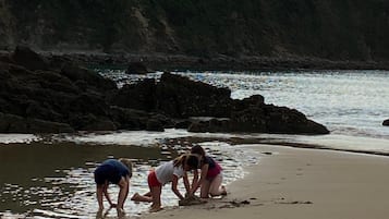 A beach with rocky terrain and a clear view of the ocean.