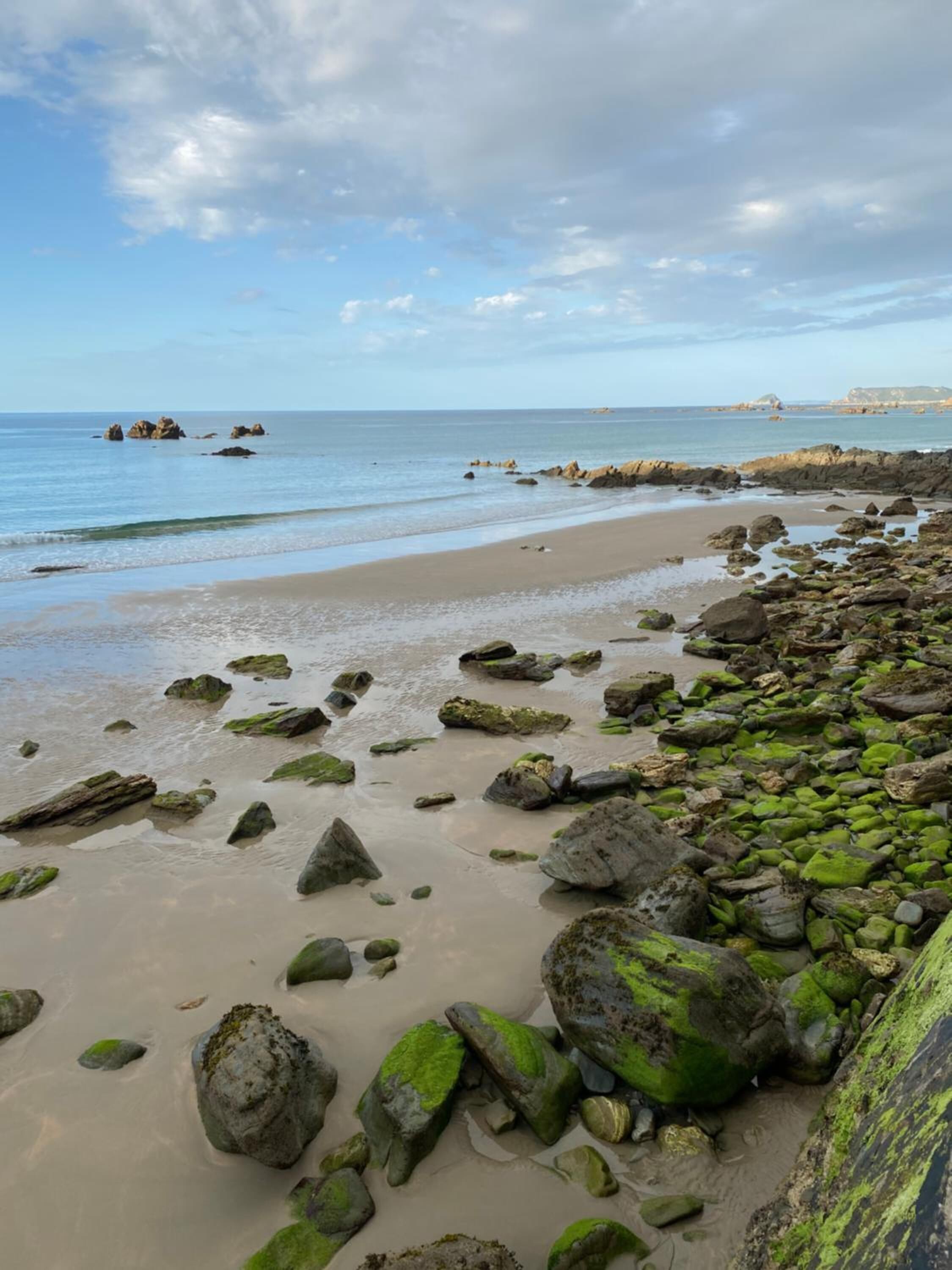 A rocky beach with large boulders and a sandy shore.