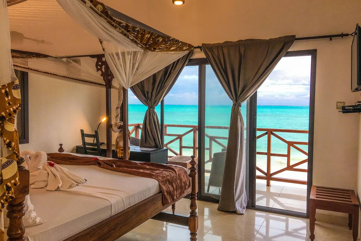 Een slaapkamer met een bed, een bureau en uitzicht op de oceaan.