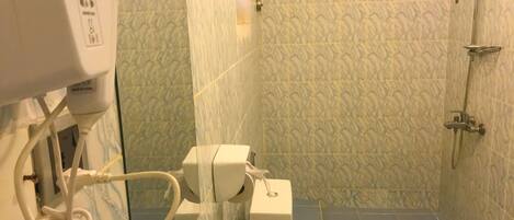 Un bagno con il water, un asciugatore di mani e una zona doccia.
