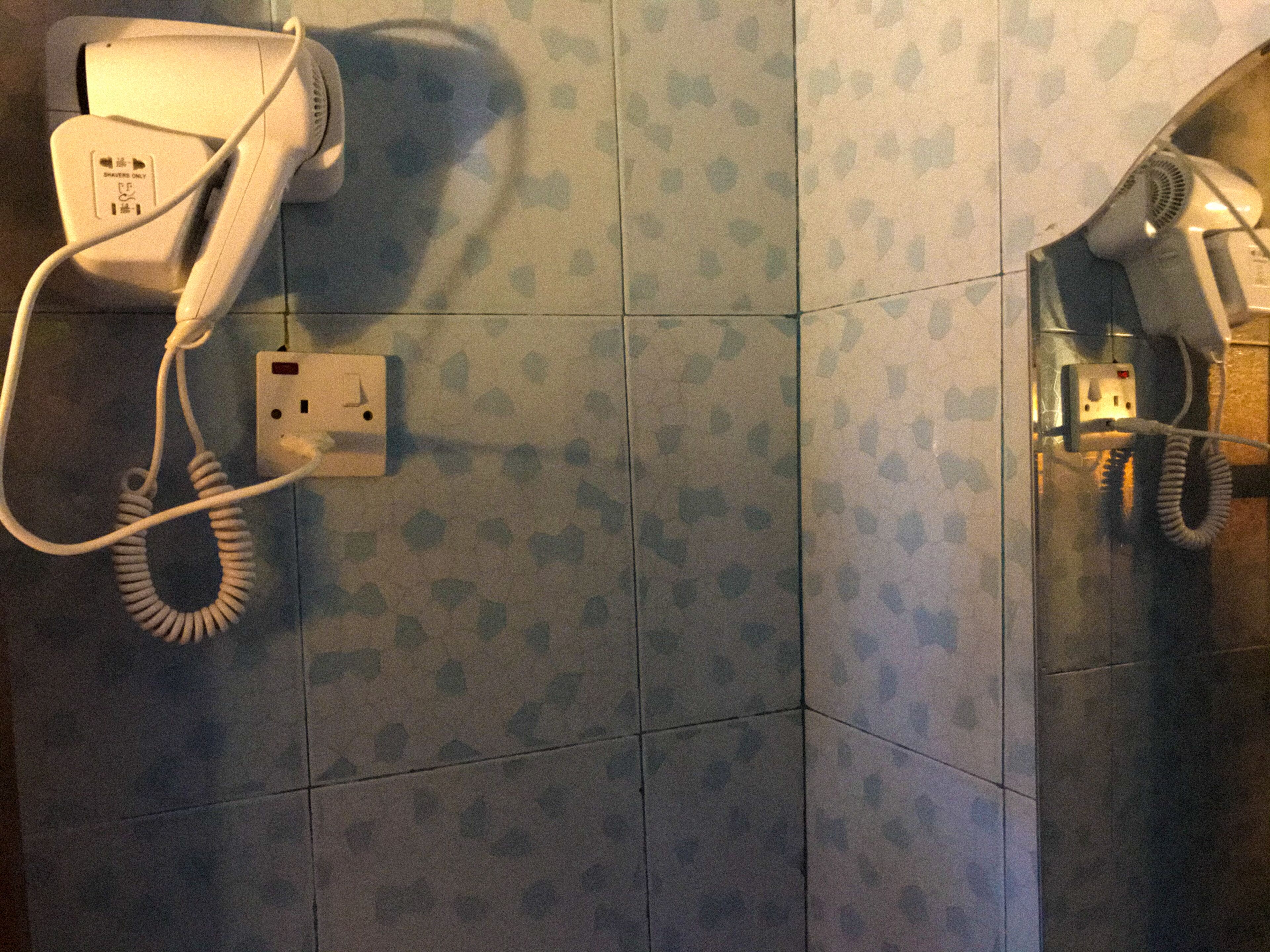 Un baño con secador de pelo y teléfono fijo en la pared.