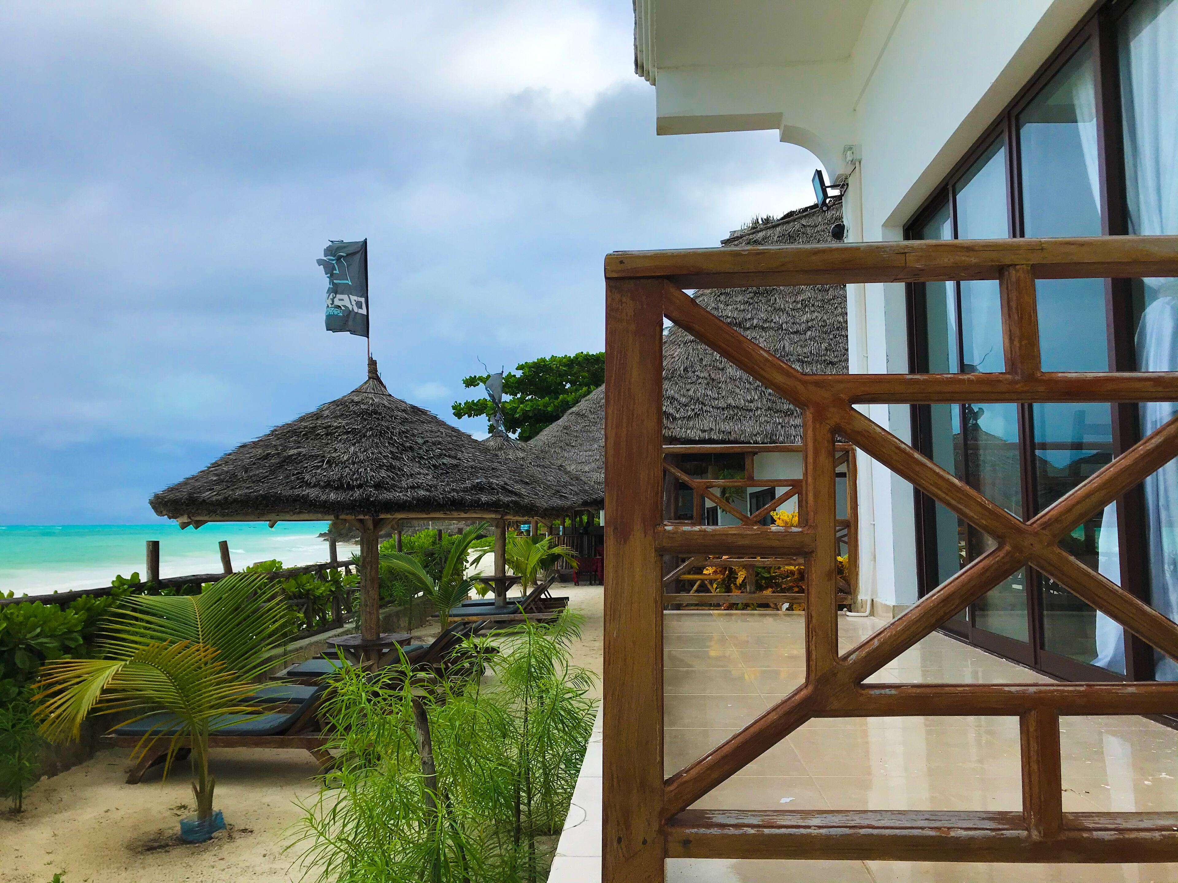 A beachside resort with thatched-roof structures, a sandy beach, and a view of the ocean.