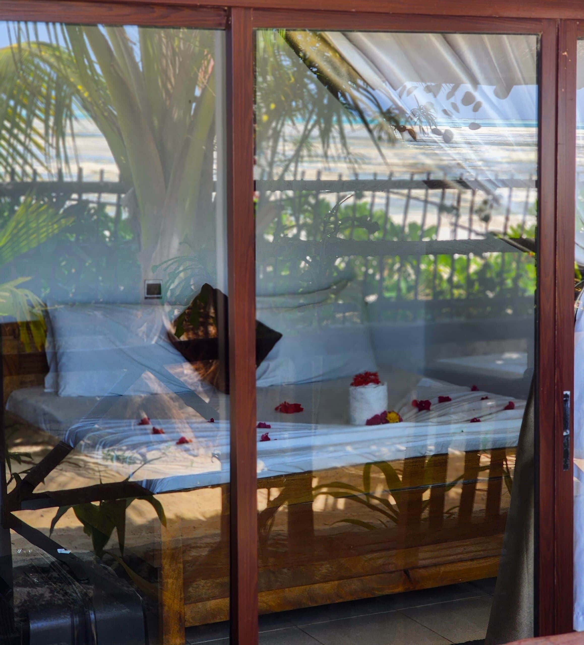 A room with a bed, a wooden table, and a glass partition.