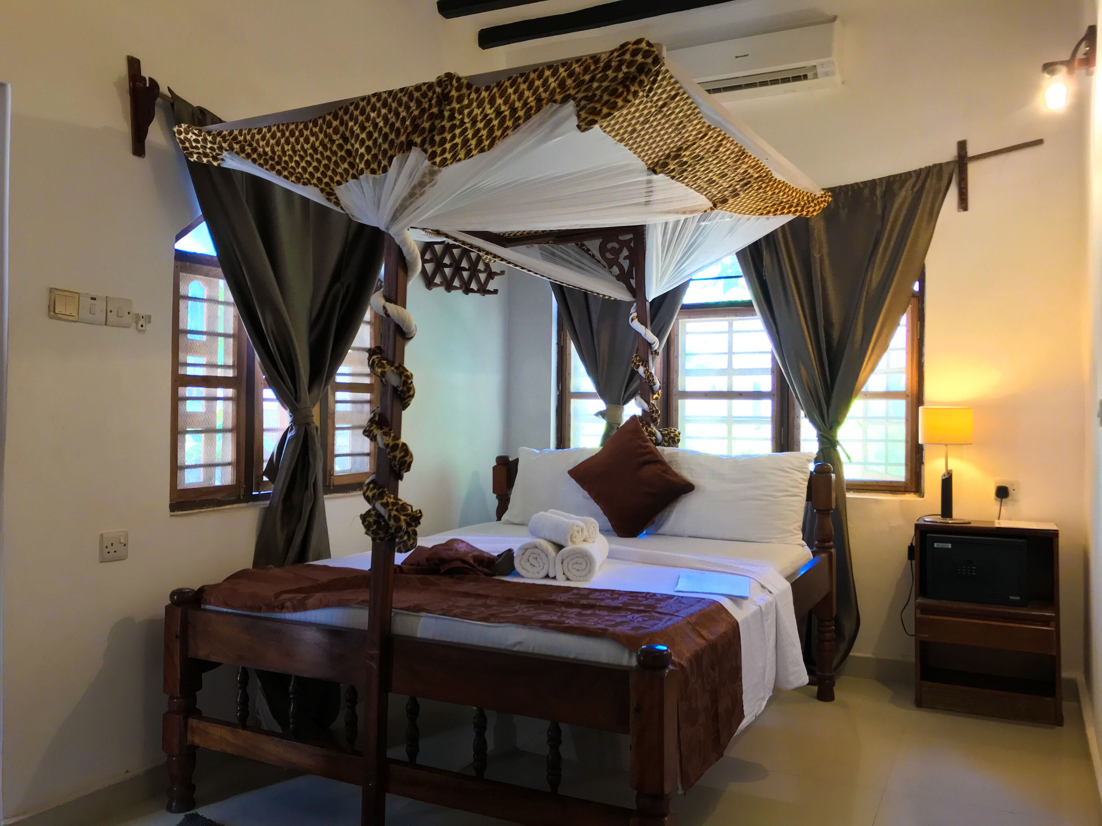 A bed with a canopy, a bedside table, and a lamp.