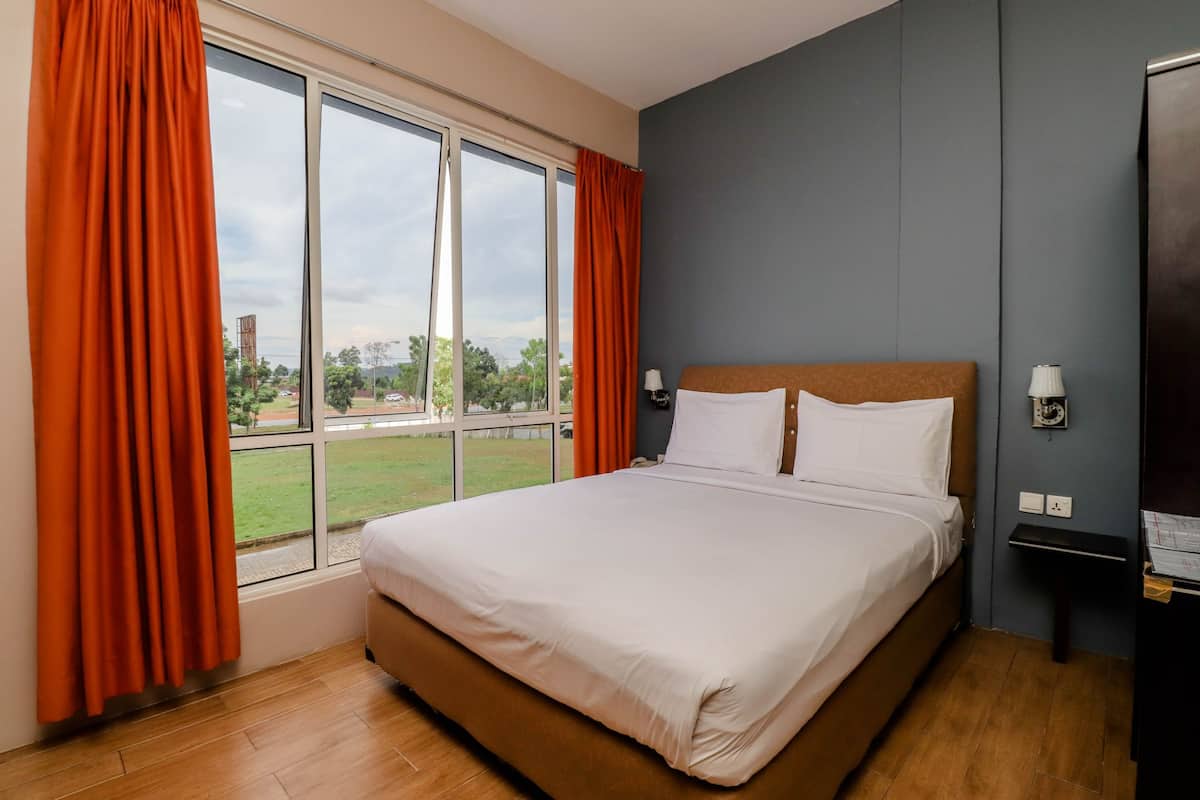 A hotel room with a large bed, two bedside tables, a window with curtains, and a view of the outdoors.
