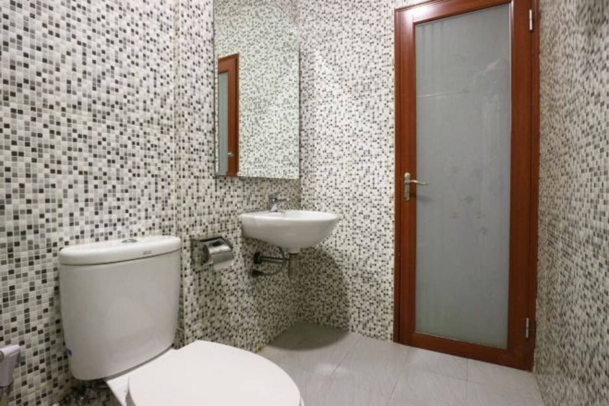 A bathroom with a toilet, sink, and mirror.