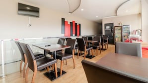 Un interior de restaurante moderno con divisiones de vidrio, mesas de madera y sillas de cuero negro.