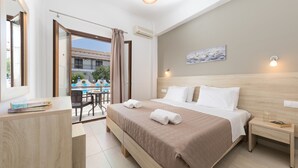 Una habitación de hotel moderna con una cama grande, un escritorio y vistas al área de la piscina exterior.