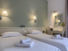 Habitación de hotel con dos camas, cada una con una toalla enrollada, una lámpara de pared y un letrero que dice “relax”.