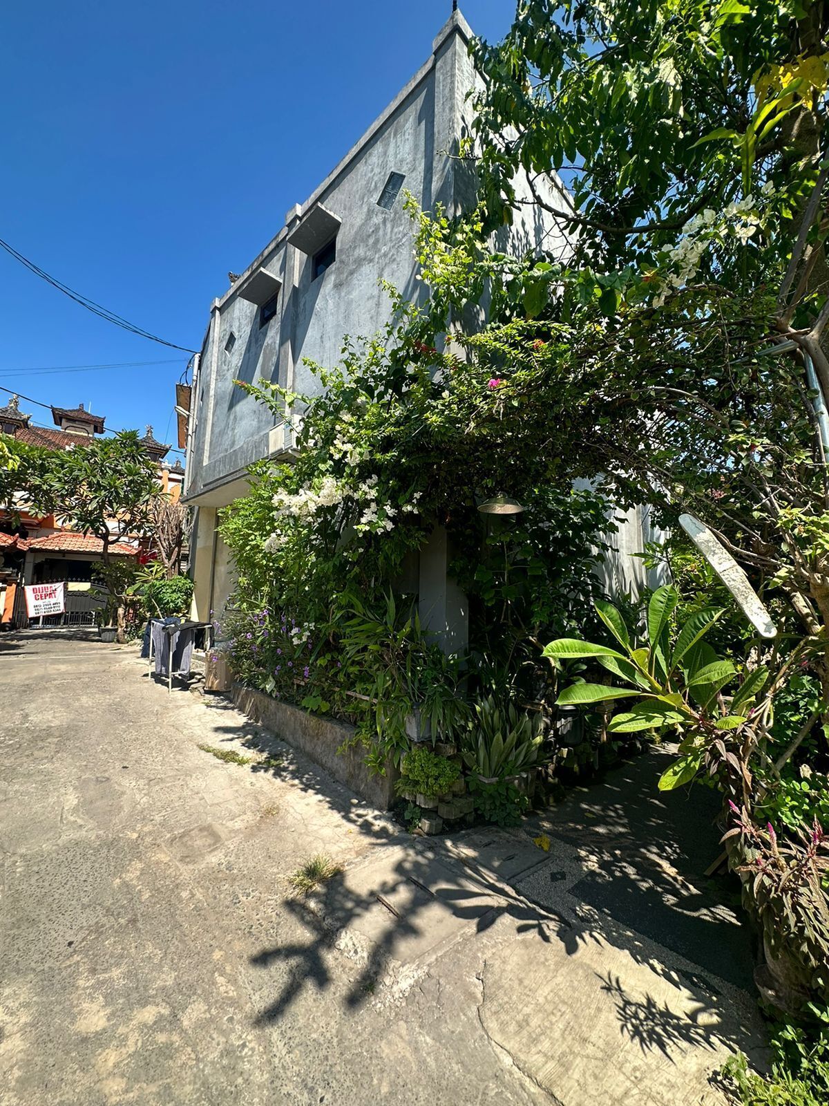 A building with a concrete facade, surrounded by lush greenery and a clear sky.