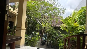 Un patio con suelo de baldosas, un banco de madera y un gato sentado sobre una alfombra.