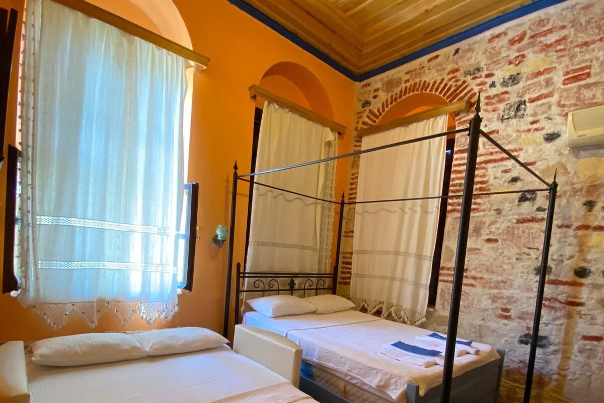 Een kamer met twee éénpersoonsbedden, een houten plafond en een bakstenen muur.