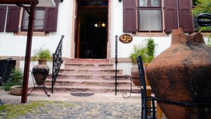 Un edificio con fachada blanca, contraventanas marrones y una entrada central con escalones.