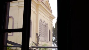 Vista a través de una ventana de un edificio de estilo arquitectónico clásico, con ventanas arqueadas y una fachada simétrica.