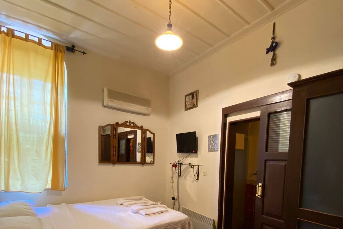 Een hotelkamer met twee bedden, een stoel, een televisie en een deur naar een andere kamer.