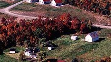 A rural area with several small houses with red roofs, a winding road, and autumn-colored trees.
