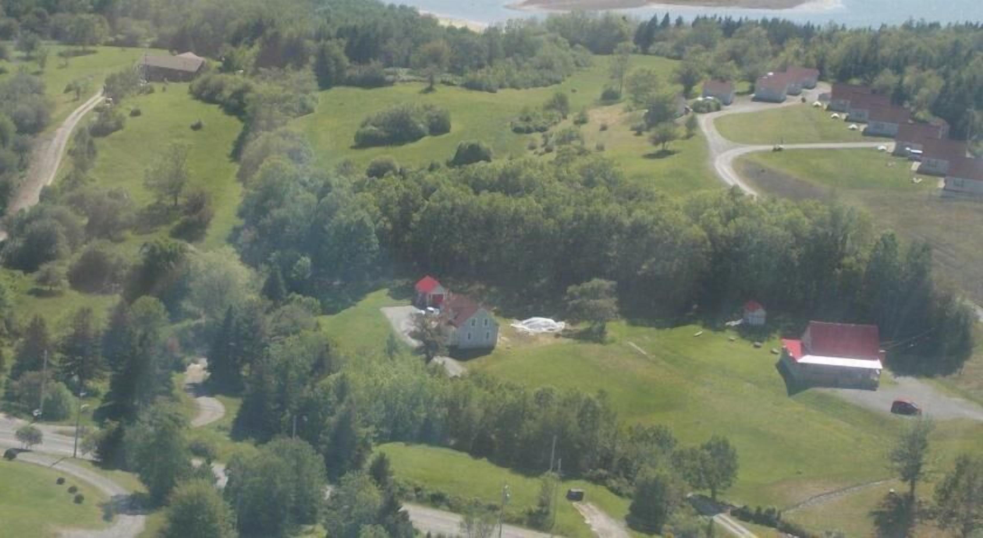 Vista aérea de una zona rural con casas dispersas, caminos y vegetación.