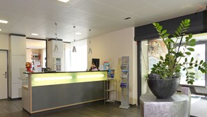 A reception area with a counter, a plant, and a glass door leading outside.