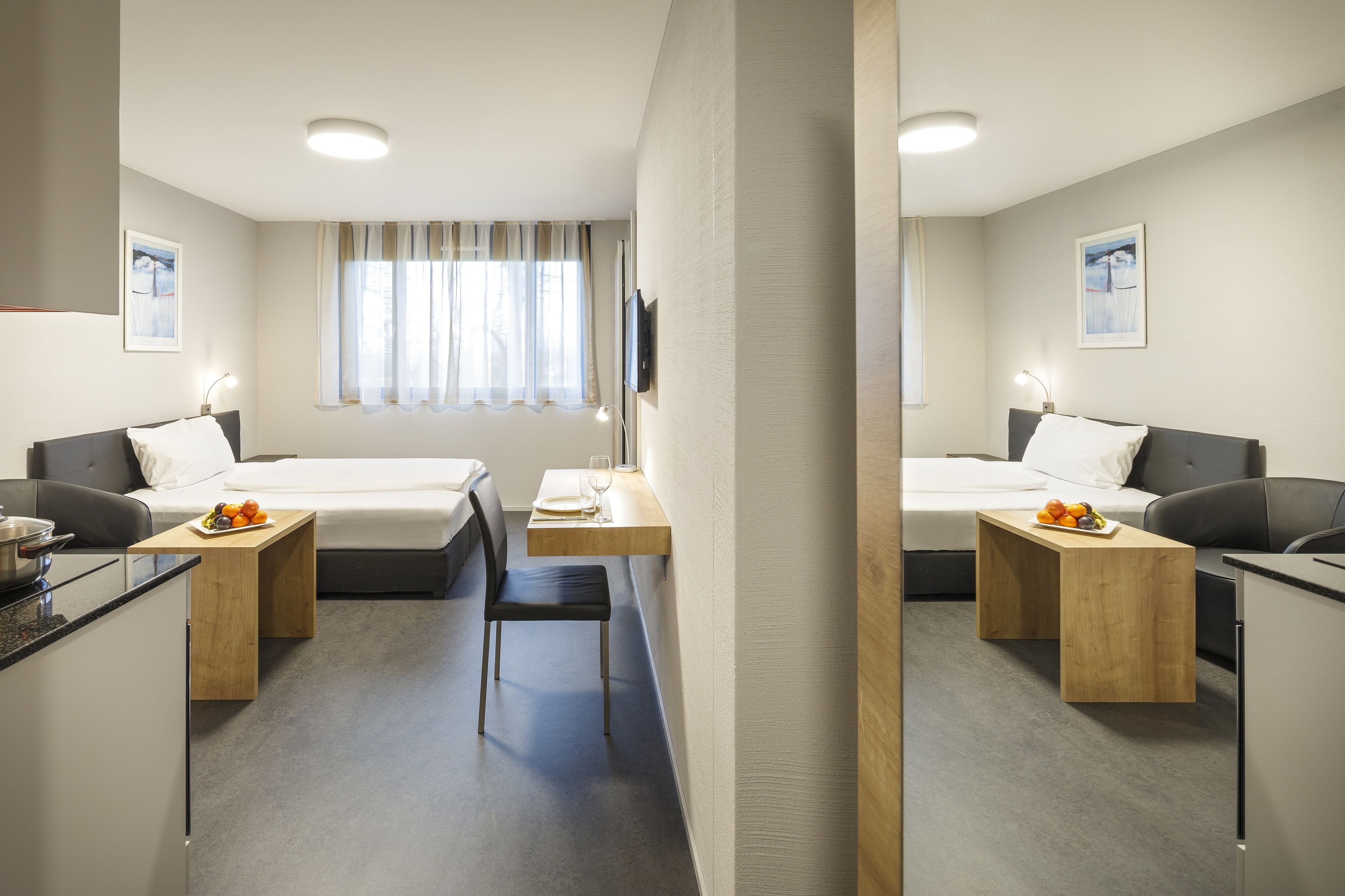 Habitación de hotel con dos camas, un escritorio, una silla y un televisor.
