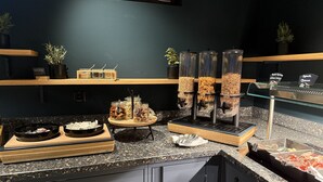 A buffet setup with various food items, including nuts, granola, and seafood.