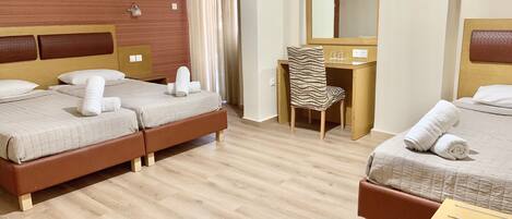 A hotel room with two beds, a desk, a chair, a mirror, and a window with curtains.