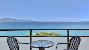 A balcony with two chairs and a small table, overlooking a calm sea and distant hills. - Hotel Flisvos (Kalamata)