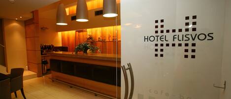 A modern hotel lobby with a reception desk, seating area, and a cafe-bar.