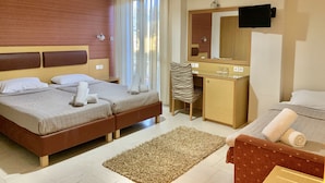 A hotel room with two beds, a desk, a chair, a TV, and a large mirror. - Hotel Flisvos (Kalamata)