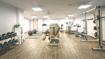 A gym with various exercise equipment, including treadmills, elliptical machines, and weightlifting stations.