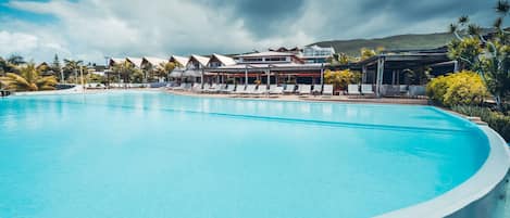 Ein großer Pool mit Liegestühlen und ein Hotelgebäude im Hintergrund.