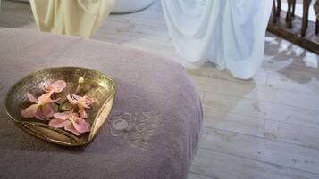 Un baño con bañera, inodoro y cortina de ducha. Hay una pequeña bandeja con flores en el suelo.