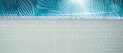 A spa area with a pool, tiled walls, and a decorative leaf pattern.