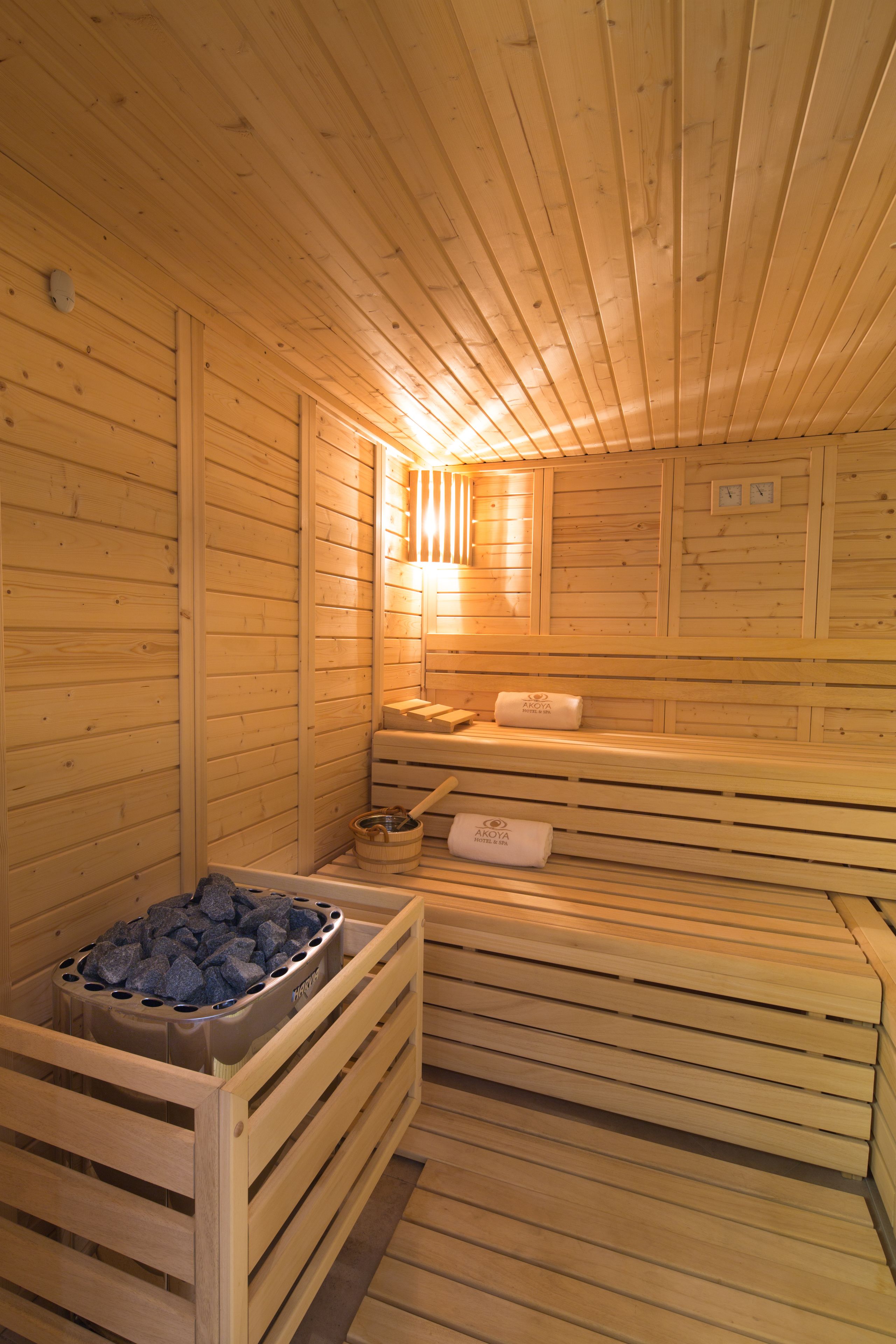 A sauna with wooden benches and a stone-filled container, likely for heating.