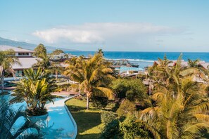 A resort with a pool, palm trees, and a view of the ocean. - Akoya Hotel & Spa (Saint-Paul)