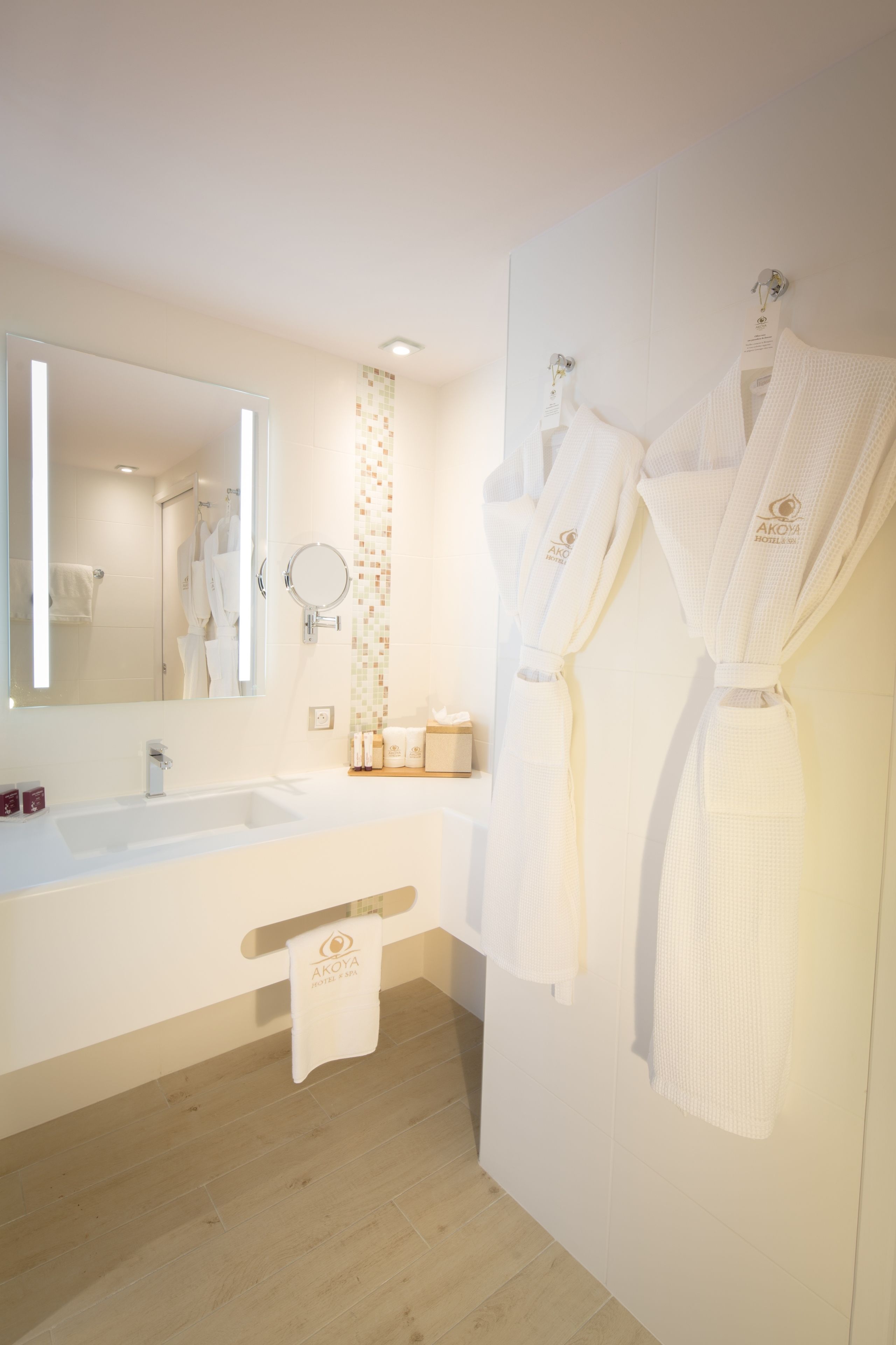 Un bagno moderno con uno specchio grande, un lavandino bianco e due asciugamani bianchi appesi al muro.