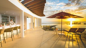 Zona de bar con vista al mar al atardecer.