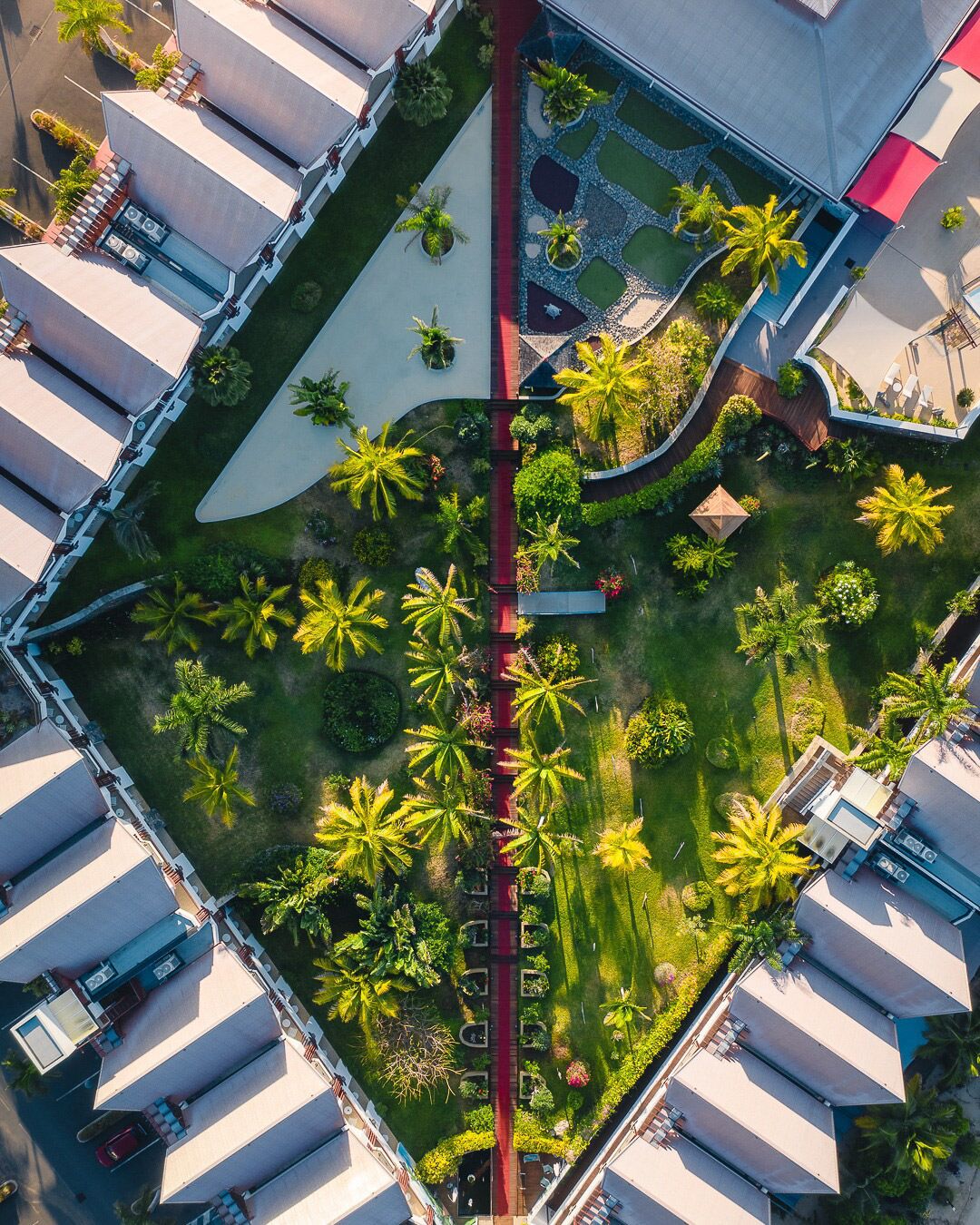 Vue aérienne d’un hôtel doté d’une cour intérieure où l’on aperçoit des palmiers et un chemin rouge.