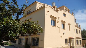 A two-story building with a stone base and a beige upper section. There are multiple windows, a visible door, and a small balcony. - Hostal El Callejón (Tarragona)