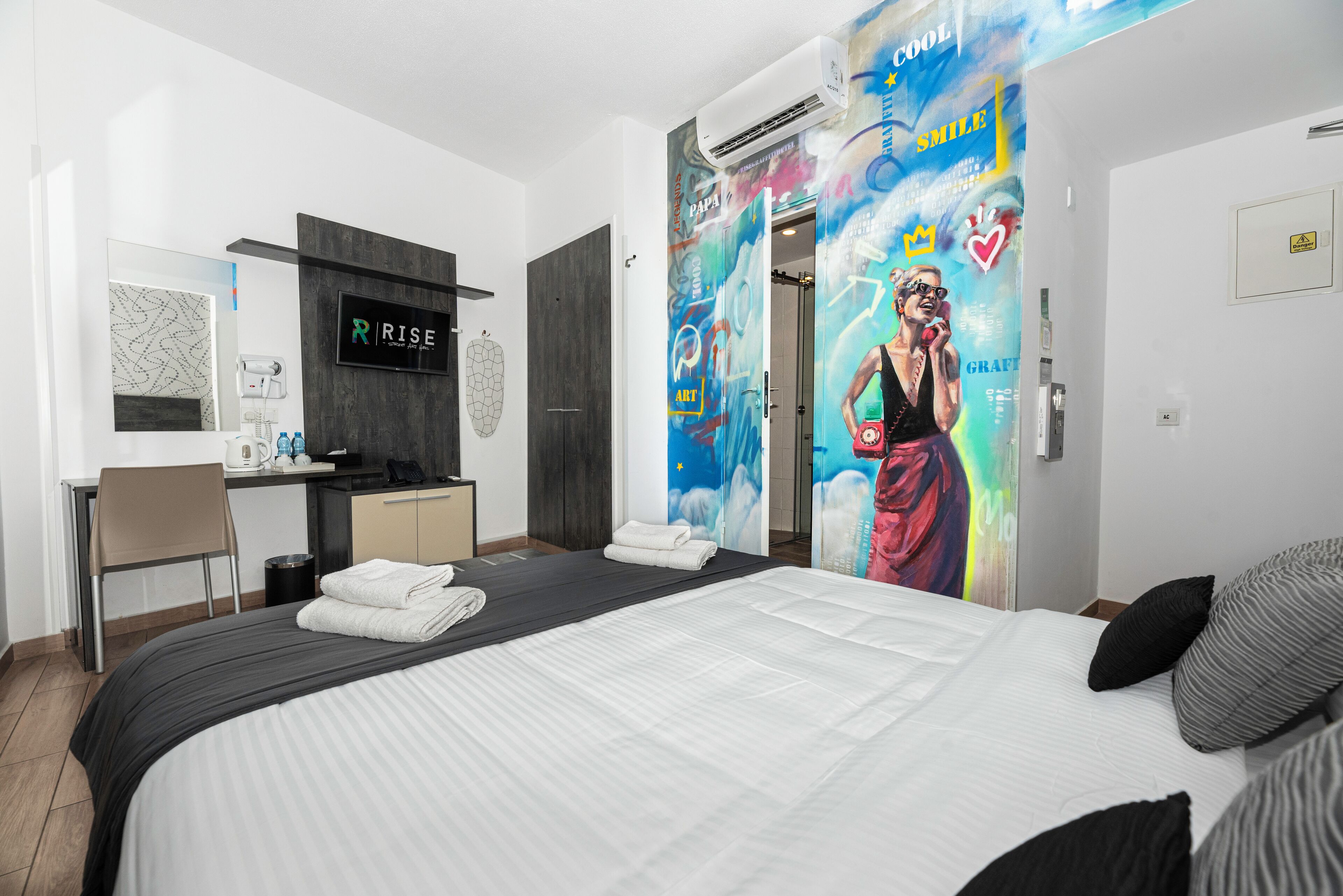 A modern hotel room with a bed, a desk, and a bathroom.