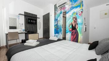 A modern hotel room with a bed, a desk, and a bathroom.